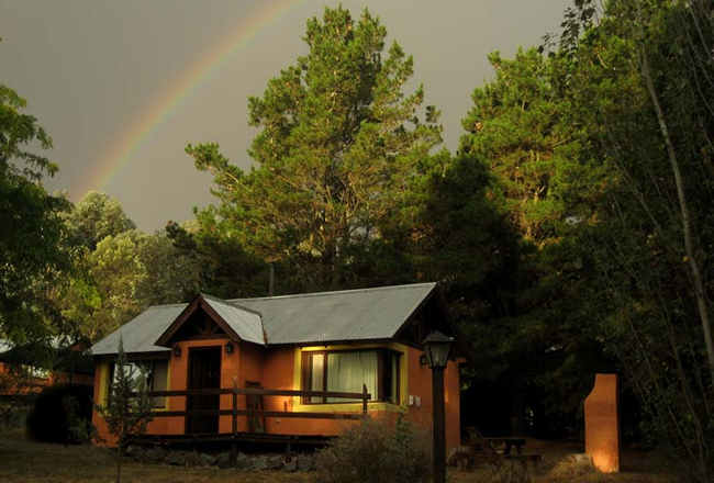 Maison fermée en forêt et arc en ciel